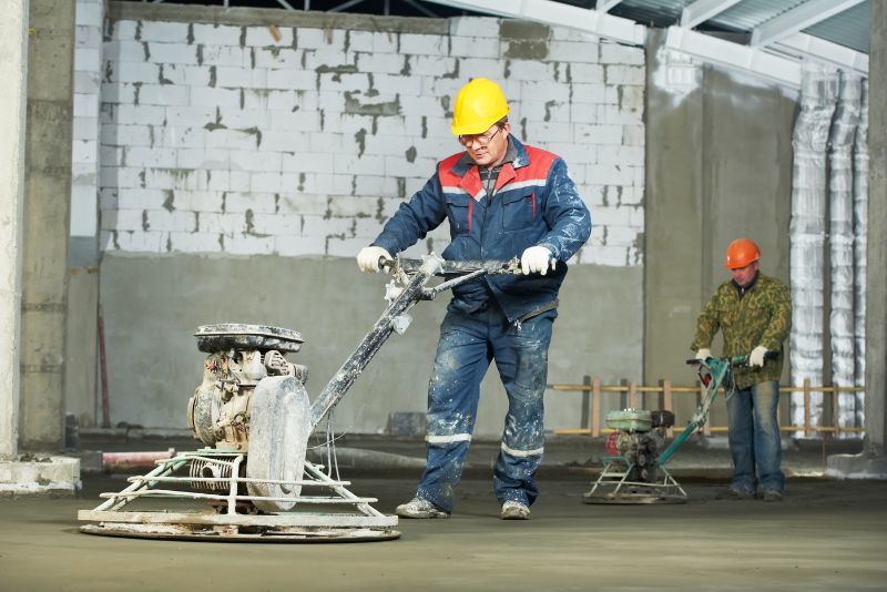 Two concrete workers levelling and finishing a residential concrete surface
