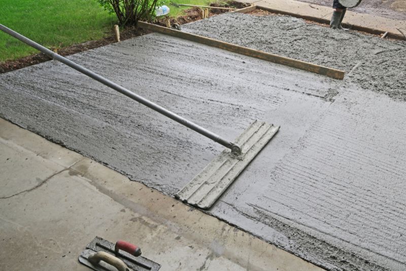 Concreter using a bull float to smooth a freshly poured slab
