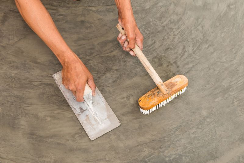 hand polishing concrete floor with wire brush and hand trowel